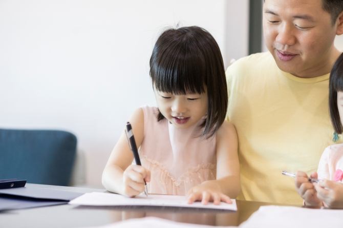 anak perempuan belajar bahasa mandarin didampingi oleh ayahnya